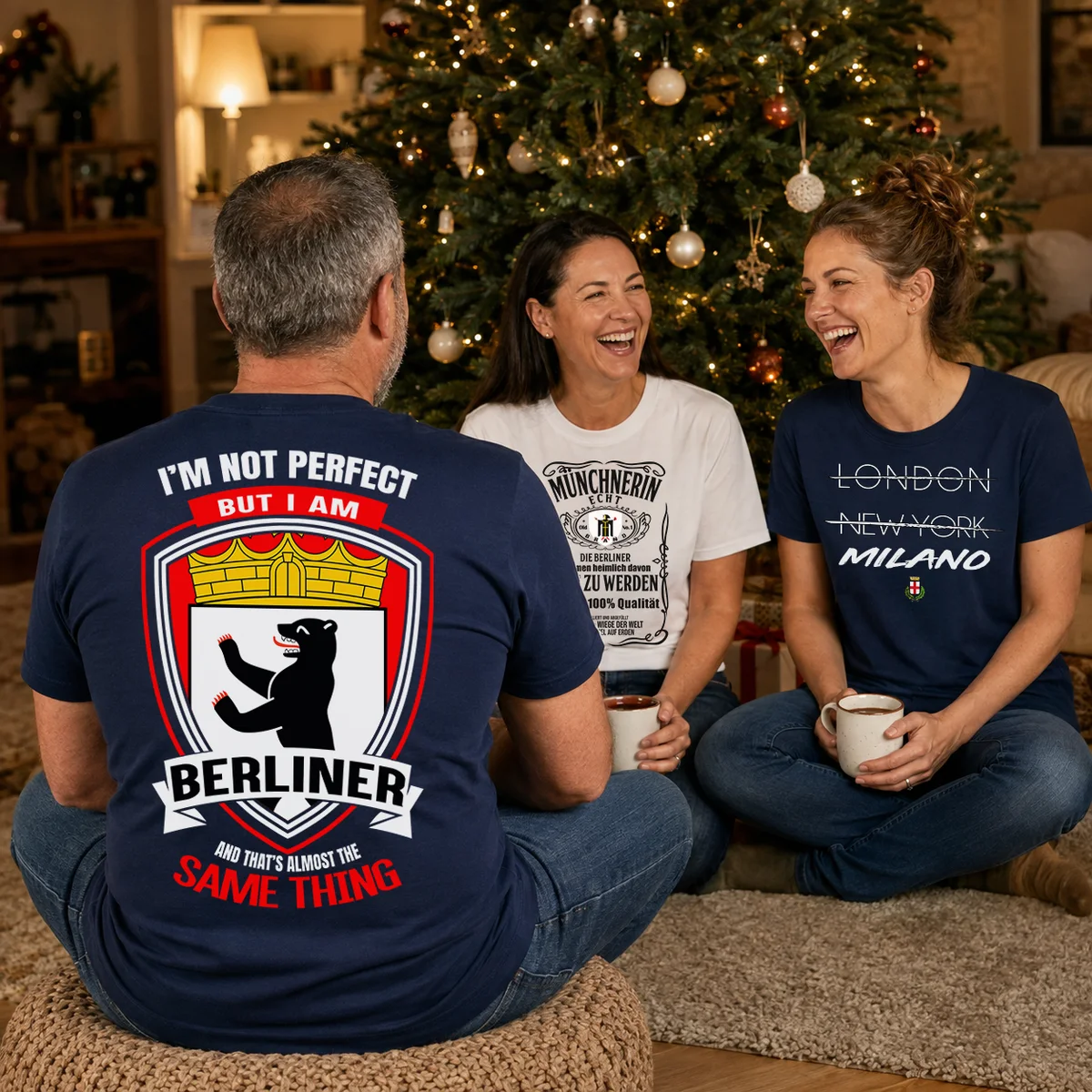 Three friends laughing by the Christmas tree in their hometown tees